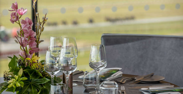 Glasses, flowers, plates and cutlery on the table overlooking the racecourse.