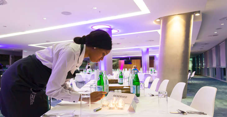 A waitress setting a table for dinner in a hall at the Aviva Stadium.