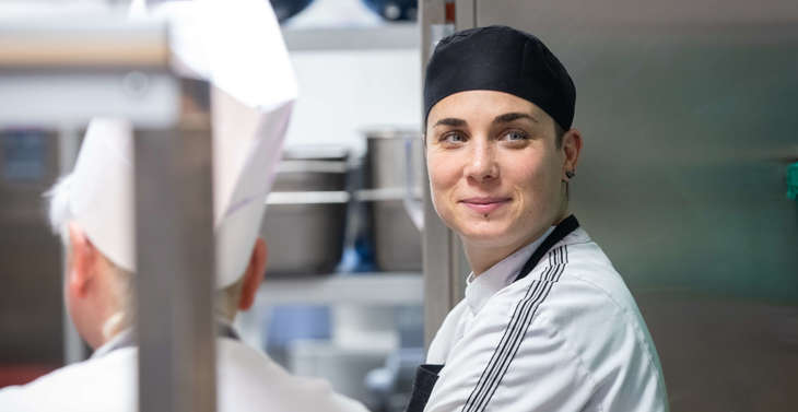 A chef looking over their shoulder in a kitchen.