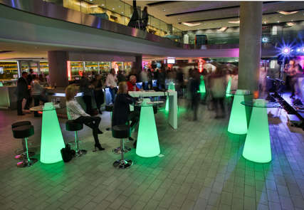 An event at the Aviva Stadium with attendees ordering drinks at a bar and sat at green tables watching a live band.
