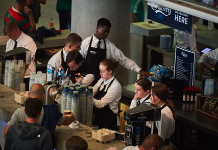 7 young members of the bar staff working the bar at an event.