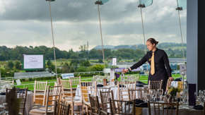 A young woman arranging and setting table decorations before an event at a racecourse.