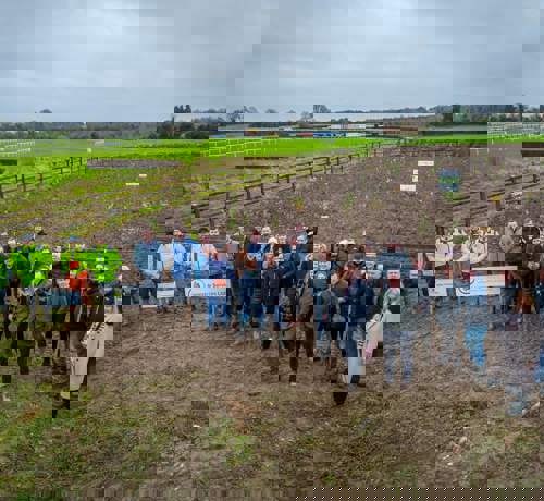 A group of people stood in a line in front of an empty field.