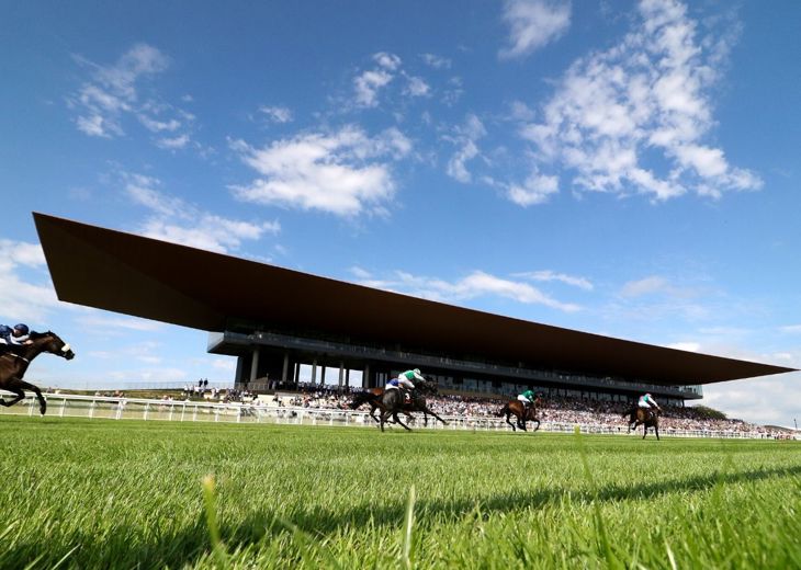 Horses taking part in a race running past a crowd in the stand at The Curragh.