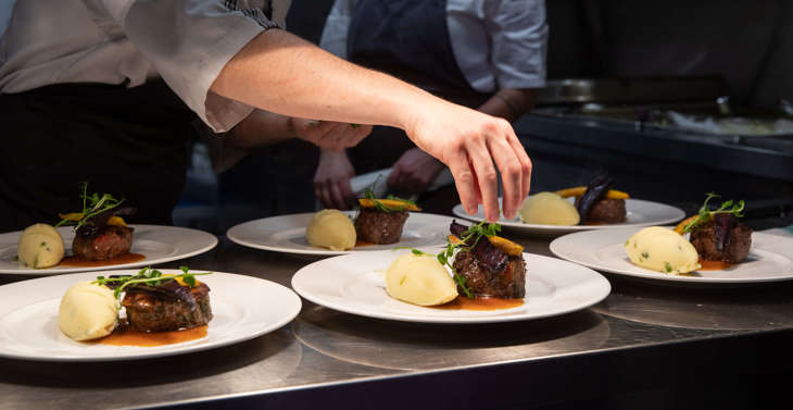 A hand preparing a plate of food on a kitchen counter.