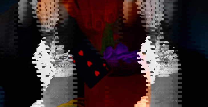 A female bartender preparing a cocktail on a wooden board decorated with playing cards and poker chips.