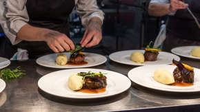 A pair of hands preparing plates of food in a kitchen.