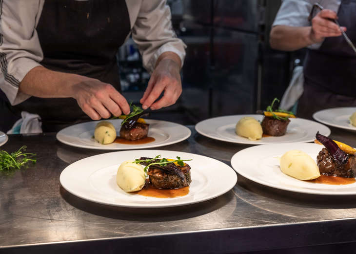 A pair of hands preparing plates of food in a kitchen.