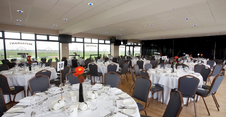A group of round tables set out for dinner in a hall at Fairyhouse.
