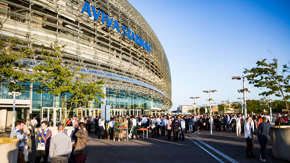 A crowd made up of different groups of people drinking and talking outside an event at the Aviva Stadium. 