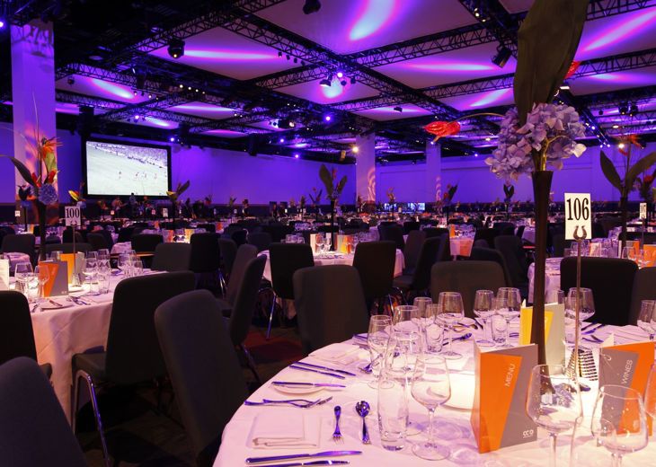 A large room with tables set up for a banquet at an awards ceremony.