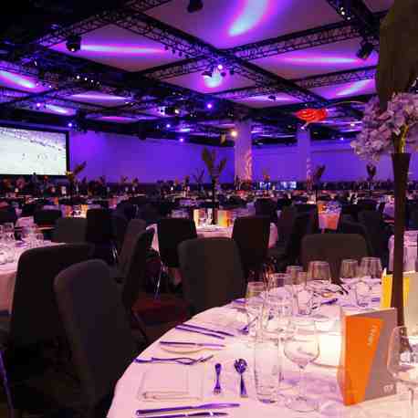 A large room with tables set up for a banquet at an awards ceremony.