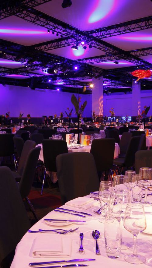 A large room with tables set up for a banquet at an awards ceremony.