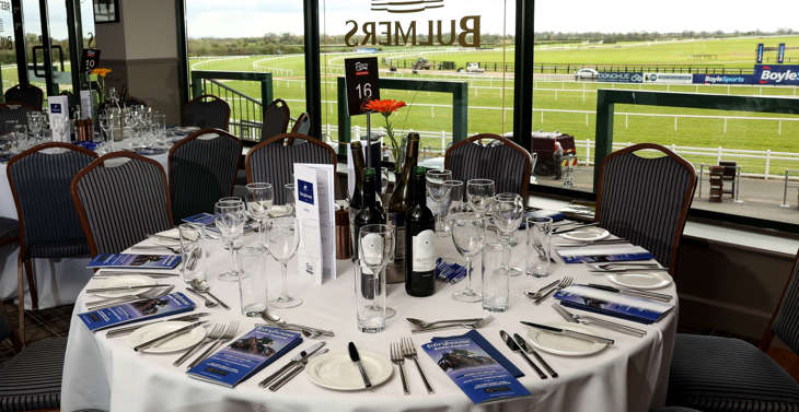 A round table set for dinner with a view of the racecourse.