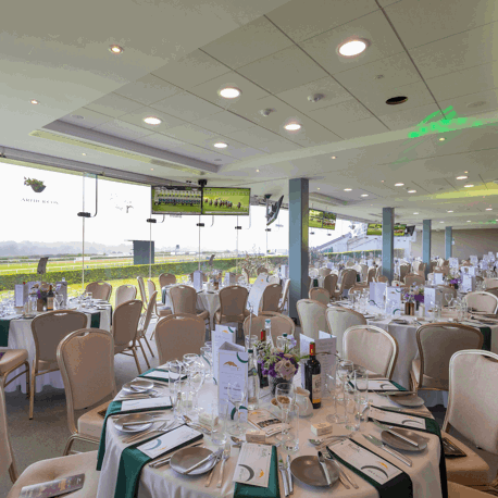 The Lower Pavilion overlooking the racecourse at Leopardstown set up for a dinner with round tables.