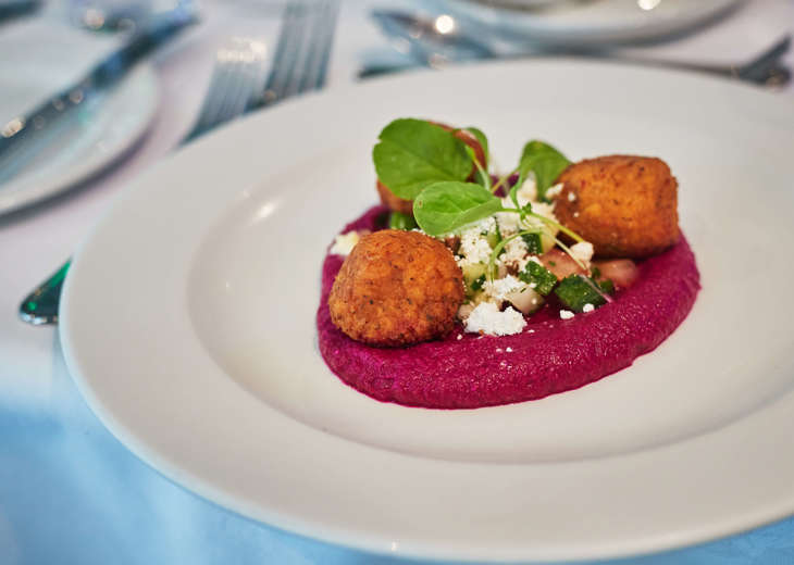 Cooked food served with a pink sauce on a white plate.