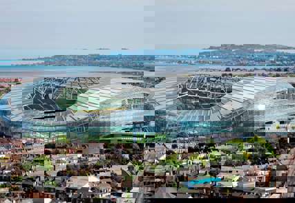 An aerial view of the Aviva stadium, the surrounding houses and the waterfront behind.