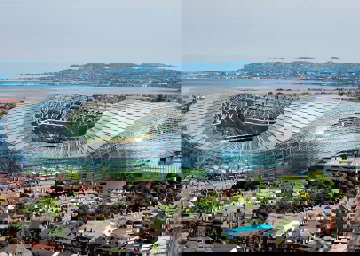 An aerial view of the Aviva stadium, the surrounding houses and the waterfront behind.